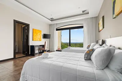 a white bedroom with a large bed and a desk at Villa Buena Onda All Inclusive in Coco