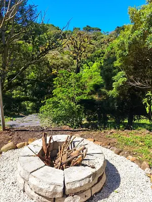 a stone fire pit in a field with trees at Kenai Mountain View in Concepción