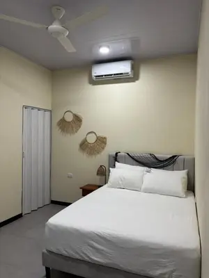 a bedroom with a white bed with two mirrors on the wall at Casa Mar Azul in Quepos