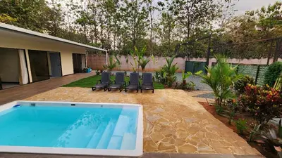 a swimming pool with two chairs and a house at Casa Mar Azul in Quepos