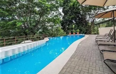 a swimming pool with chairs and an umbrella at Verde y Mar in Herradura