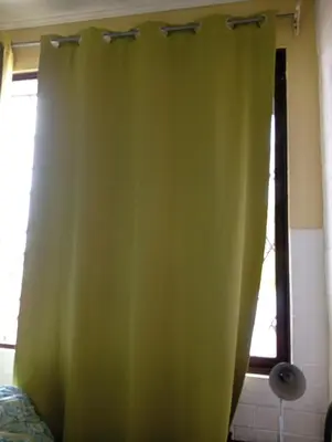 a green curtain in a room with a window at Manuel Antonio rooms in Quepos