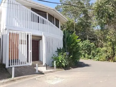 a white house with a gate in front of it at Manuel Antonio rooms in Quepos