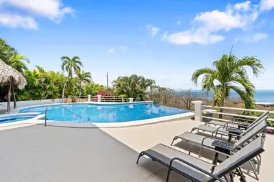 a pool with chairs and the ocean in the background at Villa Isla Azul in Ocotal