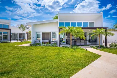 a white house with palm trees in front of it at The Enclave D9 in Playa Avellana
