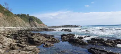 a beach with rocks and the ocean with waves at Peace at the Beach in Sámara