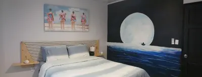 a bedroom with a bed and a painting of women on the beach at Aqua Heaven in Jabillos