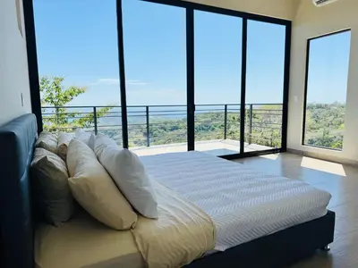 a large bed in a room with large windows at Coco Rica Luxury Oceanview Villa Pool Concierge 4 Bedroom 6BED 5BA Playa Carrillo in Carrillo