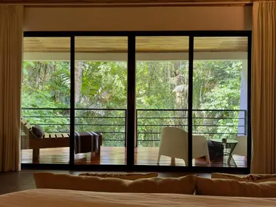 a bedroom with a large window looking out onto a deck at Jungle Bungalow at Oropel Lodge in Puerto Viejo