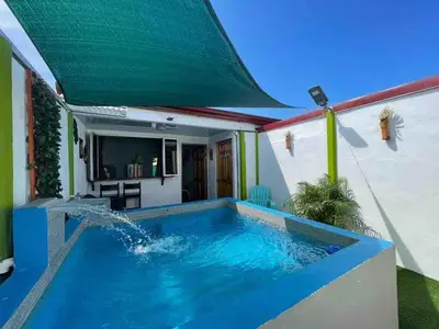 a large swimming pool with a green awning at Apartamento con piscina privada in Uvita