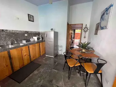 a kitchen with a table and a stainless steel refrigerator at Apartamento con piscina privada in Uvita