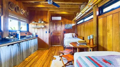 a room with two beds and a table in a train at Casa Cadejo- Incredible Surf House In Playa Grande in Playa Grande