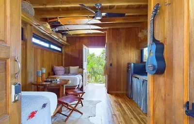 a living room with a guitar and a room with a bed and a guitar at Casa Cadejo- Incredible Surf House In Playa Grande in Playa Grande