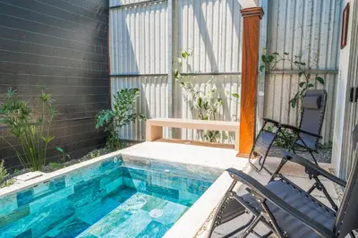 a swimming pool with two chairs next to a house at Casa Lapas in Uvita