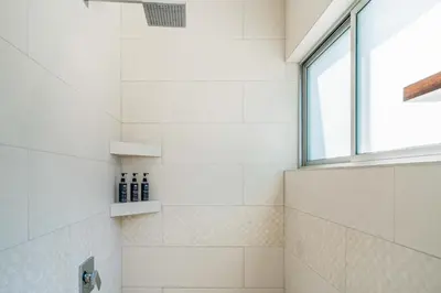 a shower with white tile and a window at Casa Lapas in Uvita