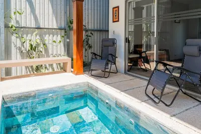 a swimming pool with two chairs next to a house at Casa Lapas in Uvita