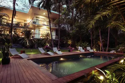 a resort with a swimming pool with chairs and a building at Om at Namaste Oasis Condo in Nosara