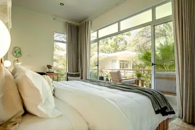 a bedroom with a white bed and a large window at Om at Namaste Oasis Condo in Nosara