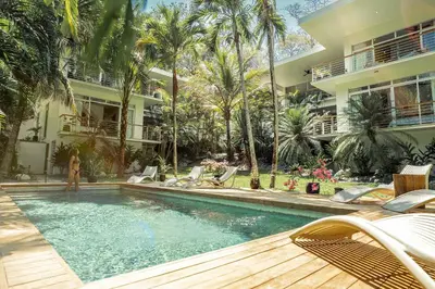 a swimming pool with chairs and a building at Prana at Namaste Oasis Condo in Nosara