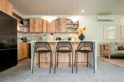 a kitchen with a counter with three stools at Prana at Namaste Oasis Condo in Nosara