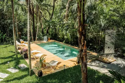 a swimming pool in the middle of a yard with palm trees at Prema at Namaste Oasis Condo in Nosara