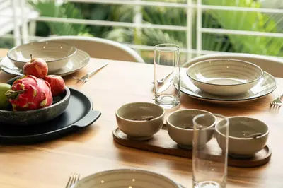 a wooden table with plates and bowls of fruit on it at Prema at Namaste Oasis Condo in Nosara