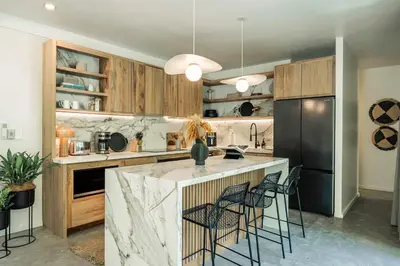 a kitchen with a counter with chairs and a refrigerator at Sukha at Namaste Oasis Condo in Nosara