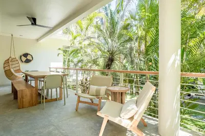 a room with a balcony with chairs and a table at Sukha at Namaste Oasis Condo in Nosara