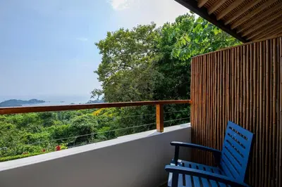 a balcony with a blue chair and a view of the ocean at Villa Kañik - Luxury Retreat with Concierge Services in Dominical