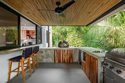 a kitchen with a stove and a counter with chairs at Villa Kañik - Luxury Retreat with Concierge Services in Dominical