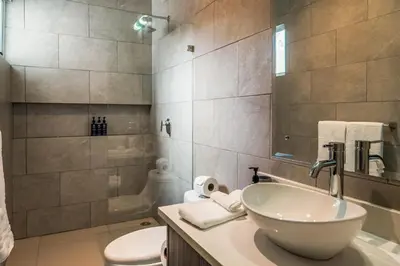 a bathroom with a sink and a toilet and a mirror at Ciudad del Mar 70 in Jacó