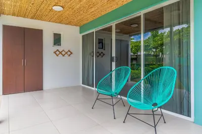 a pair of chairs on a porch with sliding glass doors at Ciudad del Mar 70 in Jacó