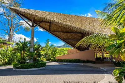 a resort with a thatched roof and palm trees at Ciudad del Mar 70 in Jacó