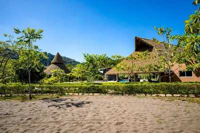 a house with a thatched roof on a beach at Ciudad del Mar 70 in Jacó