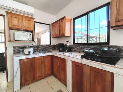 a kitchen with wooden cabinets and a large window at Casa Chika, Playa Grande Guanacaste, Casa Completa in Cuajiniquil