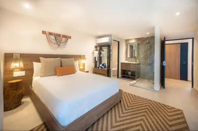 a bedroom with a large bed and a bathroom at Lia Hotel Jaco - Adults Only in Jacó