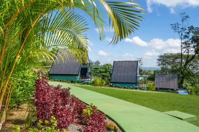 a walkway through a park with flowers and buildings at Junglo Resort and Spa in Fortuna