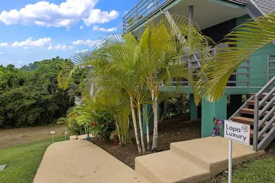 a palm tree in front of a building with a sign at Junglo Resort and Spa in Fortuna
