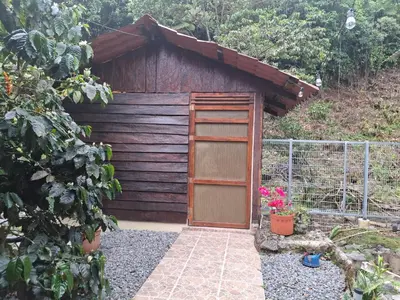 a wooden shed with a door in a garden at Aire Agua y Naturaleza in Guácimo