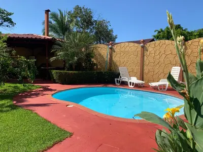a small swimming pool in a yard with two chairs at Villas BRENES in Uvita