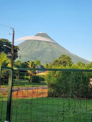 a mountain with a fence in front of a field at Arenal Cozy Retreats Villa Sloth in Fortuna