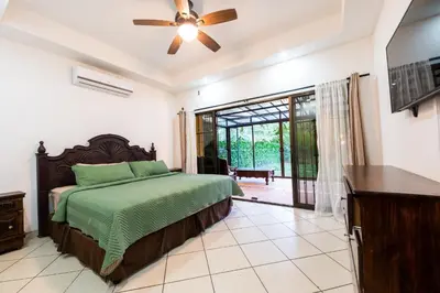 a bedroom with a bed and a ceiling fan at Villa Tropical by Vacation Pura Vida in Esterillos Este