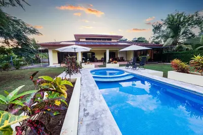a swimming pool in front of a house at Villa Tropical by Vacation Pura Vida in Esterillos Este