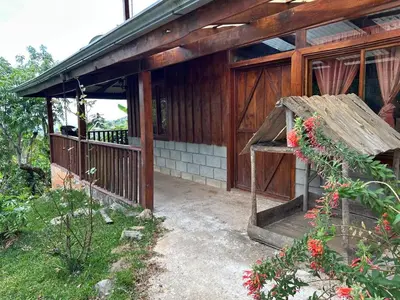 a wooden house with a porch with a bench at La Cabaña de Tuto Estate Coffees in San Pablo