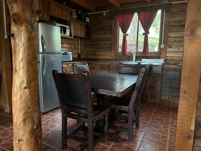 a kitchen with a wooden table and a refrigerator at La Cabaña de Tuto Estate Coffees in San Pablo