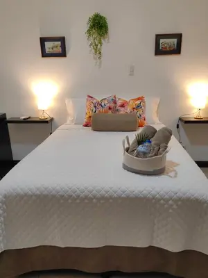 a bedroom with a large white bed with shoes on it at Hotel Boutique CasAguacate close to Airport, Pedregal, Centro de Convenciones de Costa Rica in Potrerillos