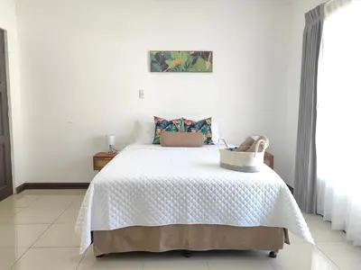 a bedroom with a bed with a white blanket at Hotel Boutique CasAguacate close to Airport, Pedregal, Centro de Convenciones de Costa Rica in Potrerillos
