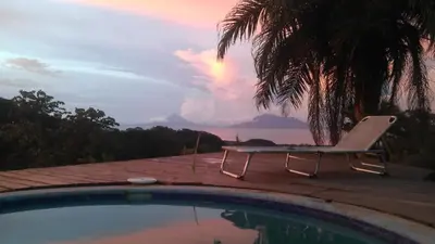 a chair sitting next to a swimming pool with the sunset at Tierra Madre Eco Lodge in Los Andes