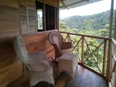 two wicker chairs sitting on the balcony of a cabin at Tierra Madre Eco Lodge in Los Andes