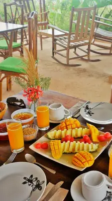 a table topped with plates of food and orange juice at Tierra Madre Eco Lodge in Los Andes